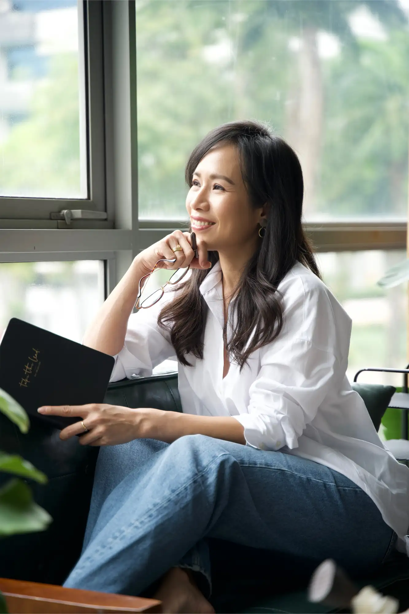 Julina Halim (Youhui), founder of Inside Out Academy Singapore and accredited nutritionist and health coach, sitting on a sofa and looking out the window