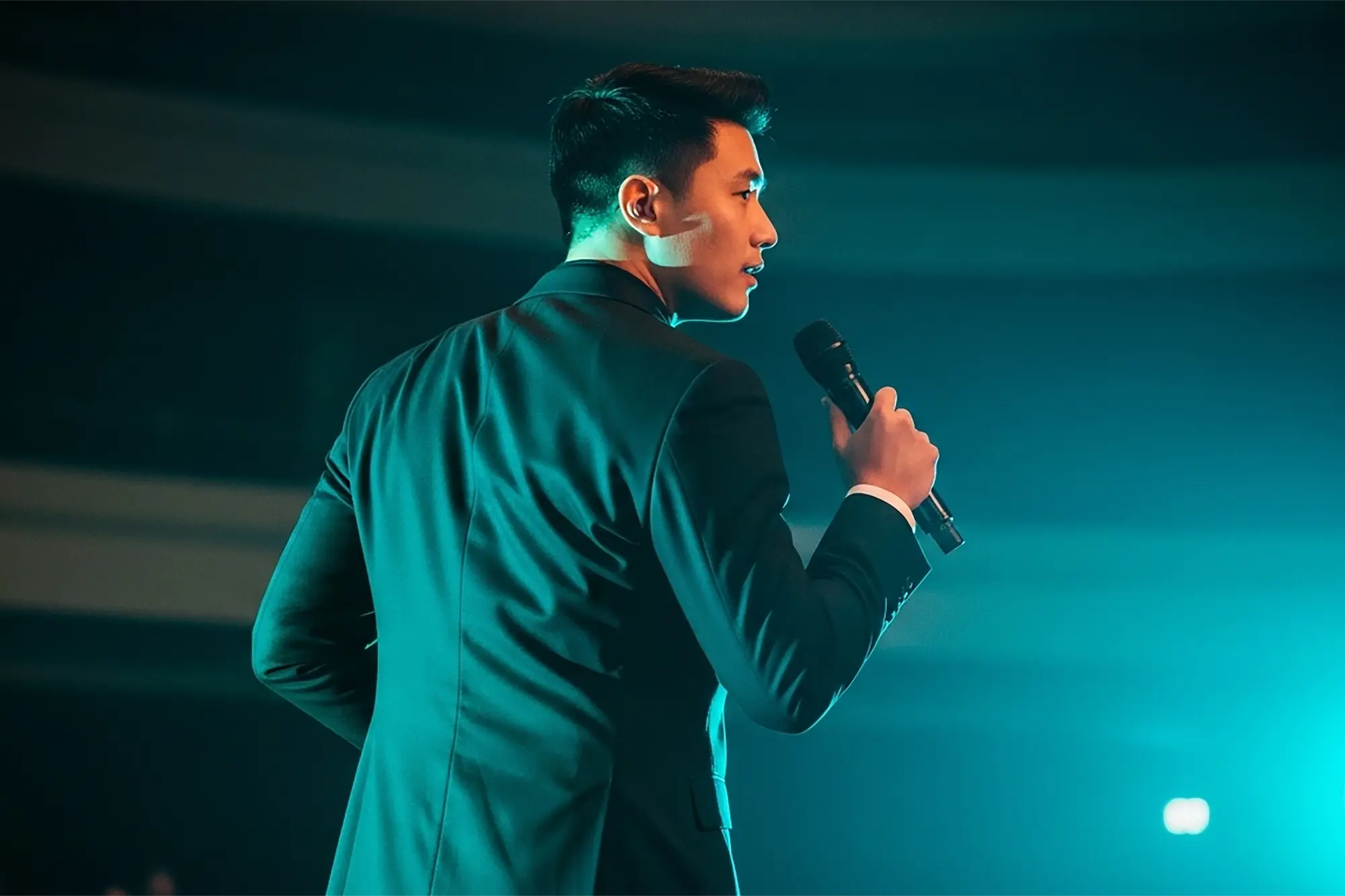 A man on stage and holding a microphone